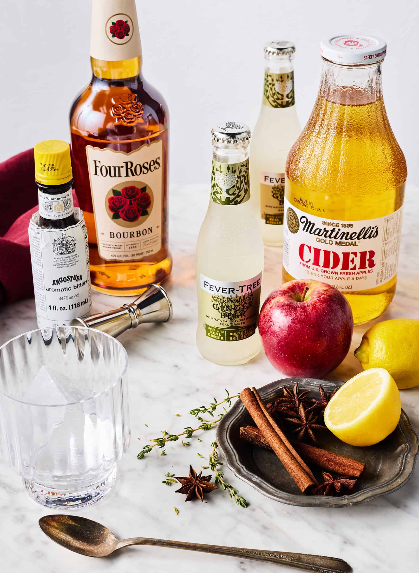 Recipe ingredients - bourbon, ginger beer, apple cider, Angostura bitters, fresh apple, lemon, and spices
