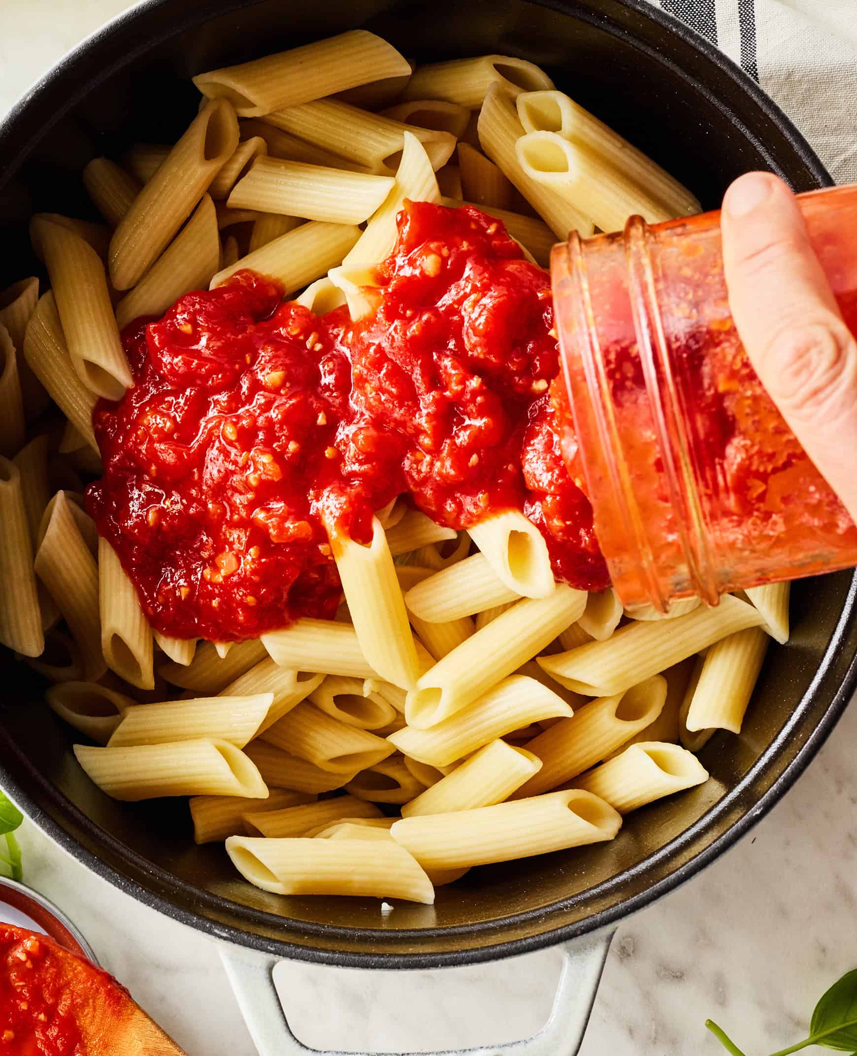 Pouring sauce over penne pasta