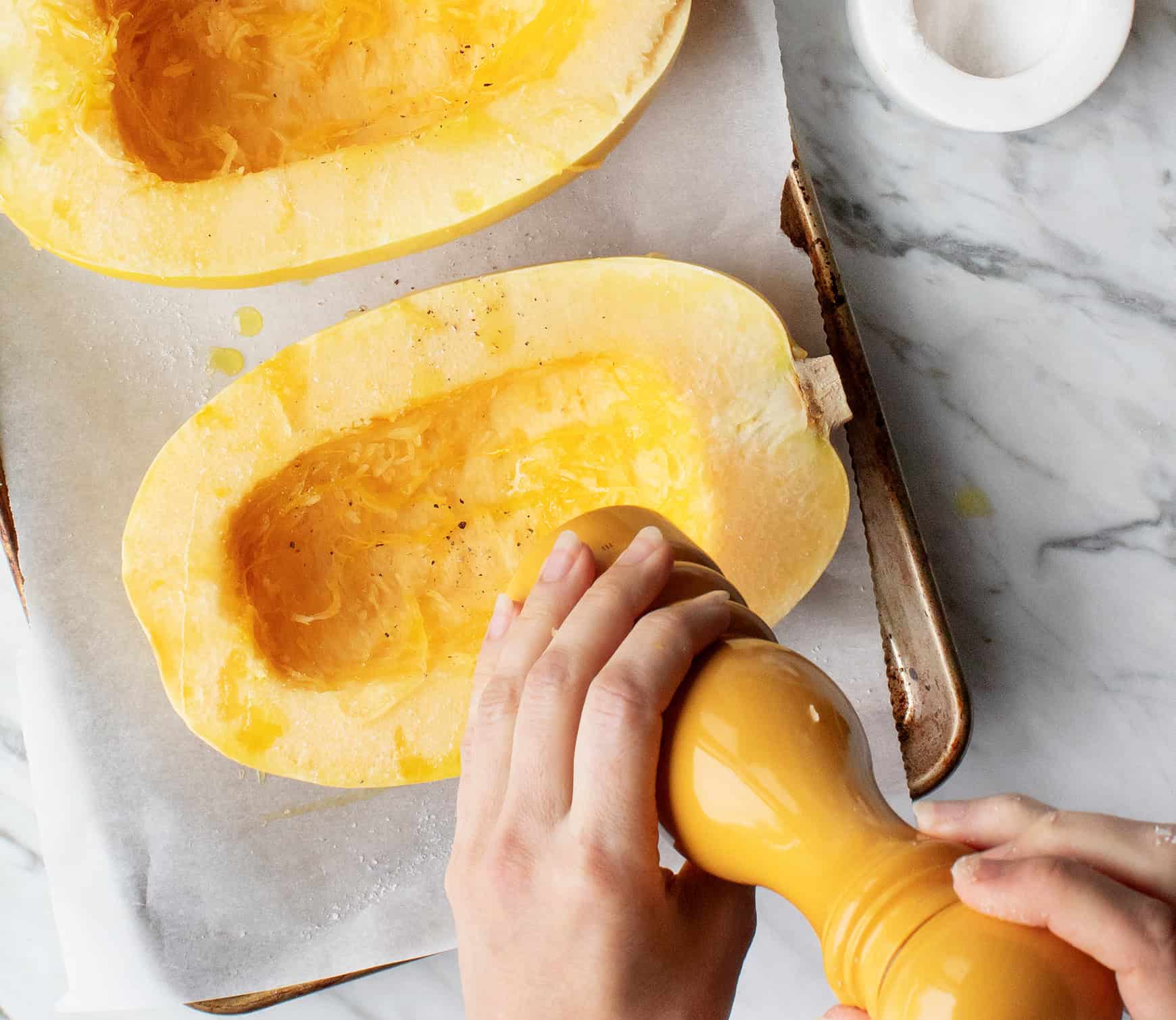 seasoning the spaghetti squash on a baking sheet