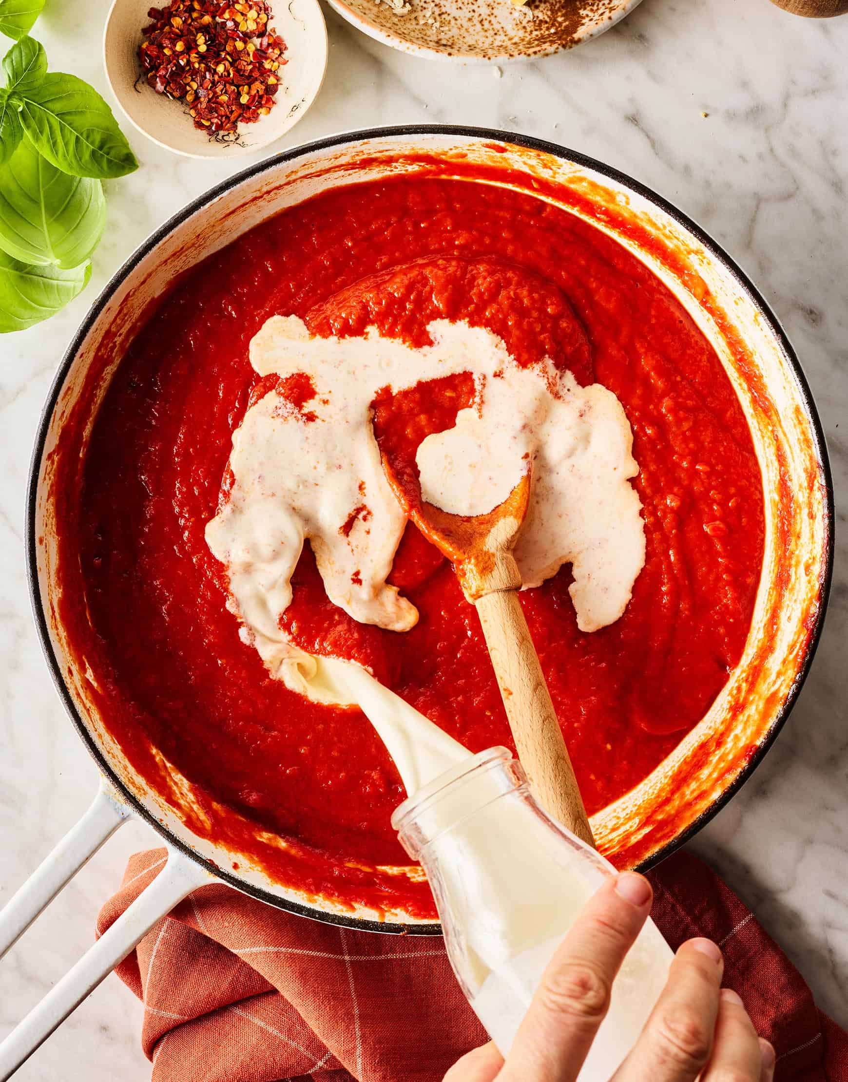 Pouring cream into tomato sauce
