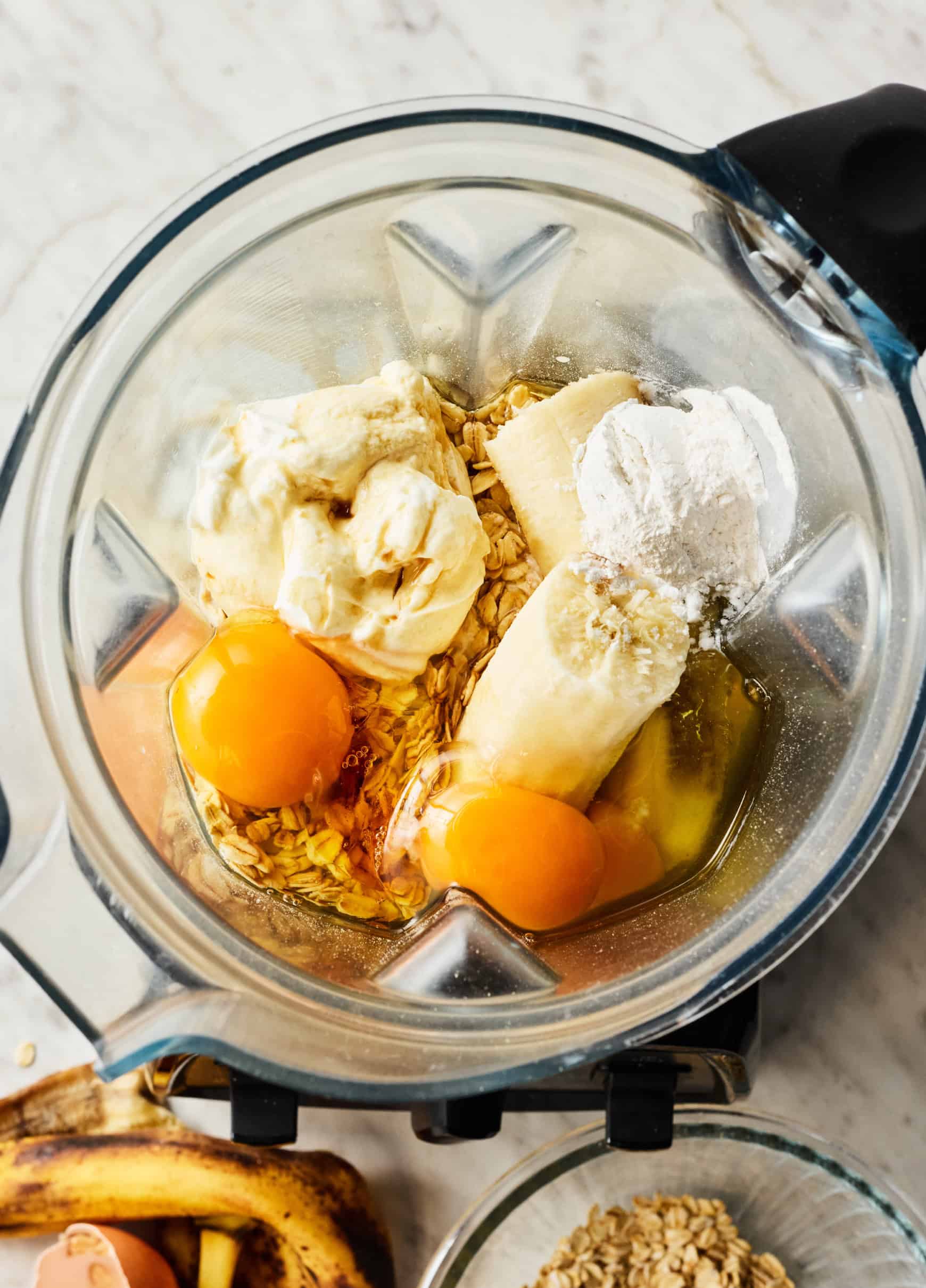 Whole rolled oats, banana, eggs, and protein powder in a blender
