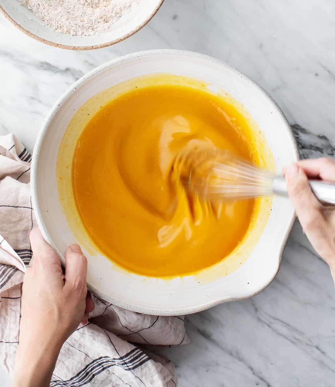 Hand whisking wet ingredients in a mixing bowl