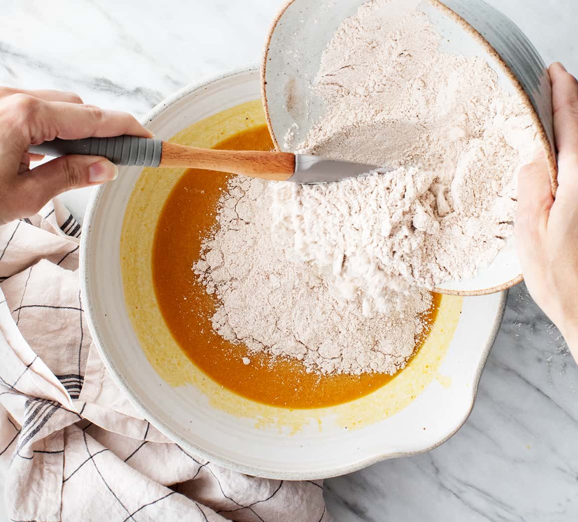 Adding dry ingredients to wet ingredients in mixing bowl