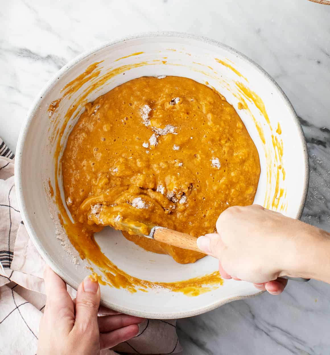Hand using spatula to stir batter for easy pumpkin bread recipe