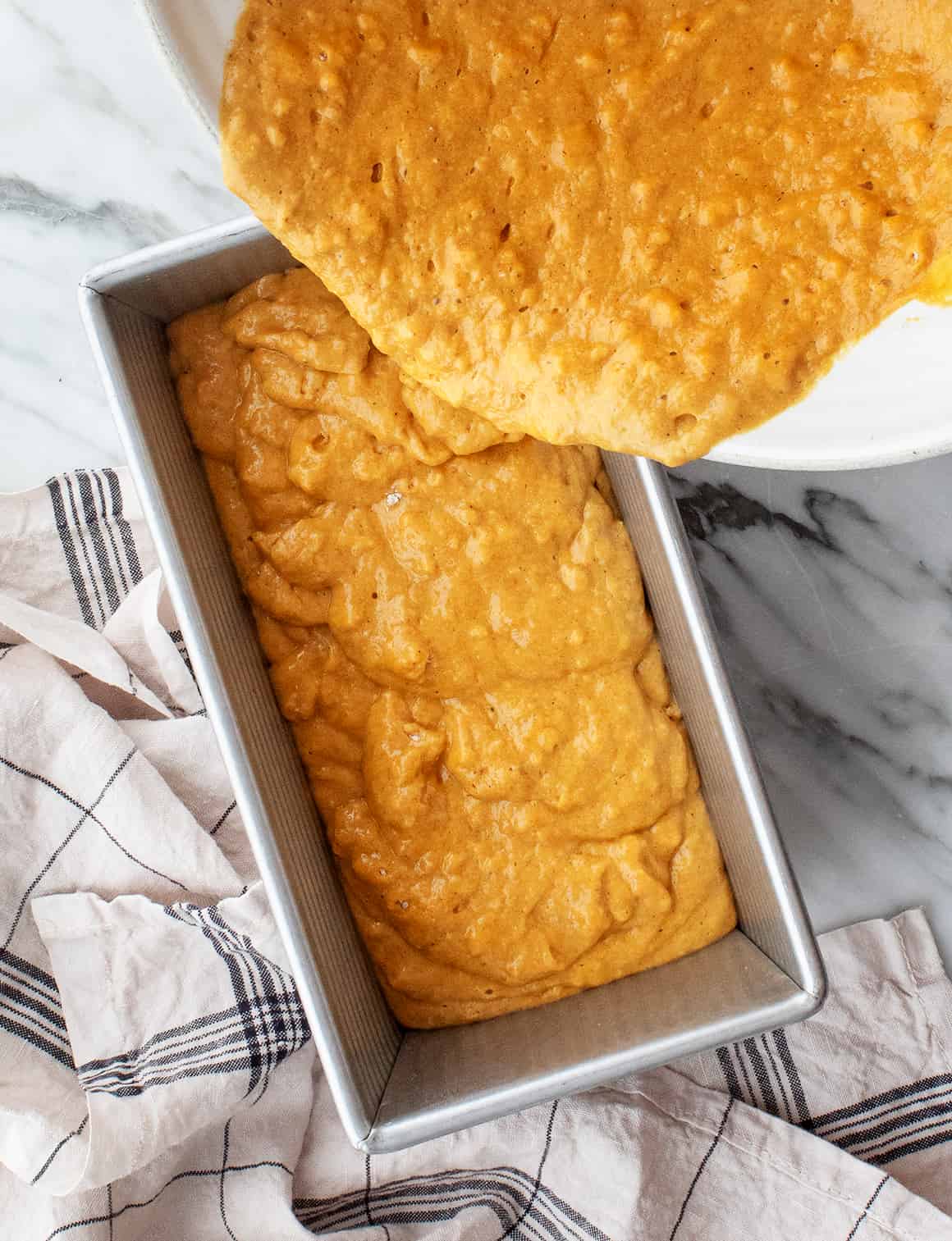 Pouring pumpkin bread batter into loaf pan
