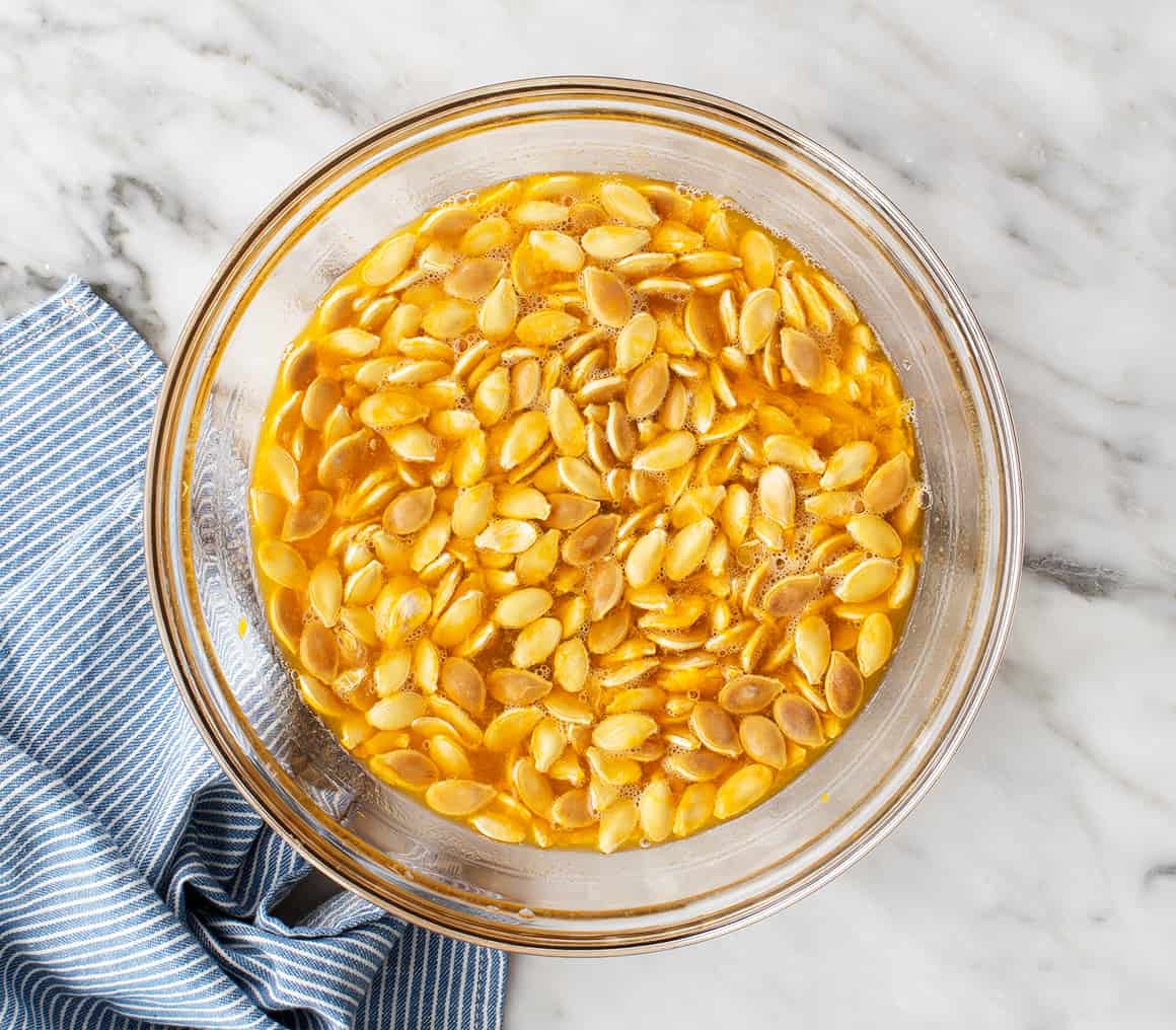Pumpkin seeds and flesh in large bowl of water