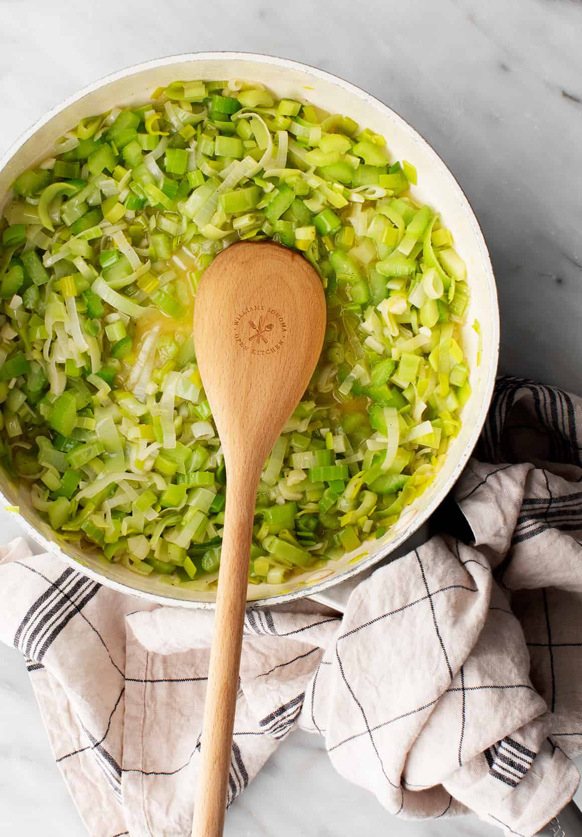 Sautéed leeks and celery in skillet with wooden spoon