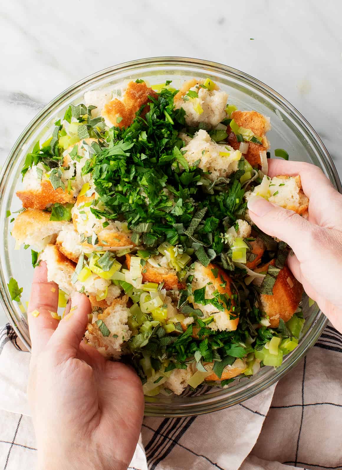 Dried bread cubes, celery, and herbs in mixing bowl