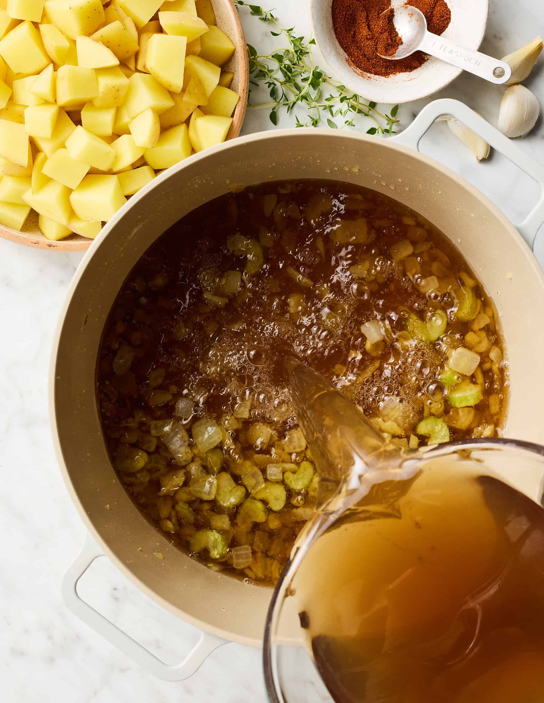 Pouring broth into pot with onions and celery