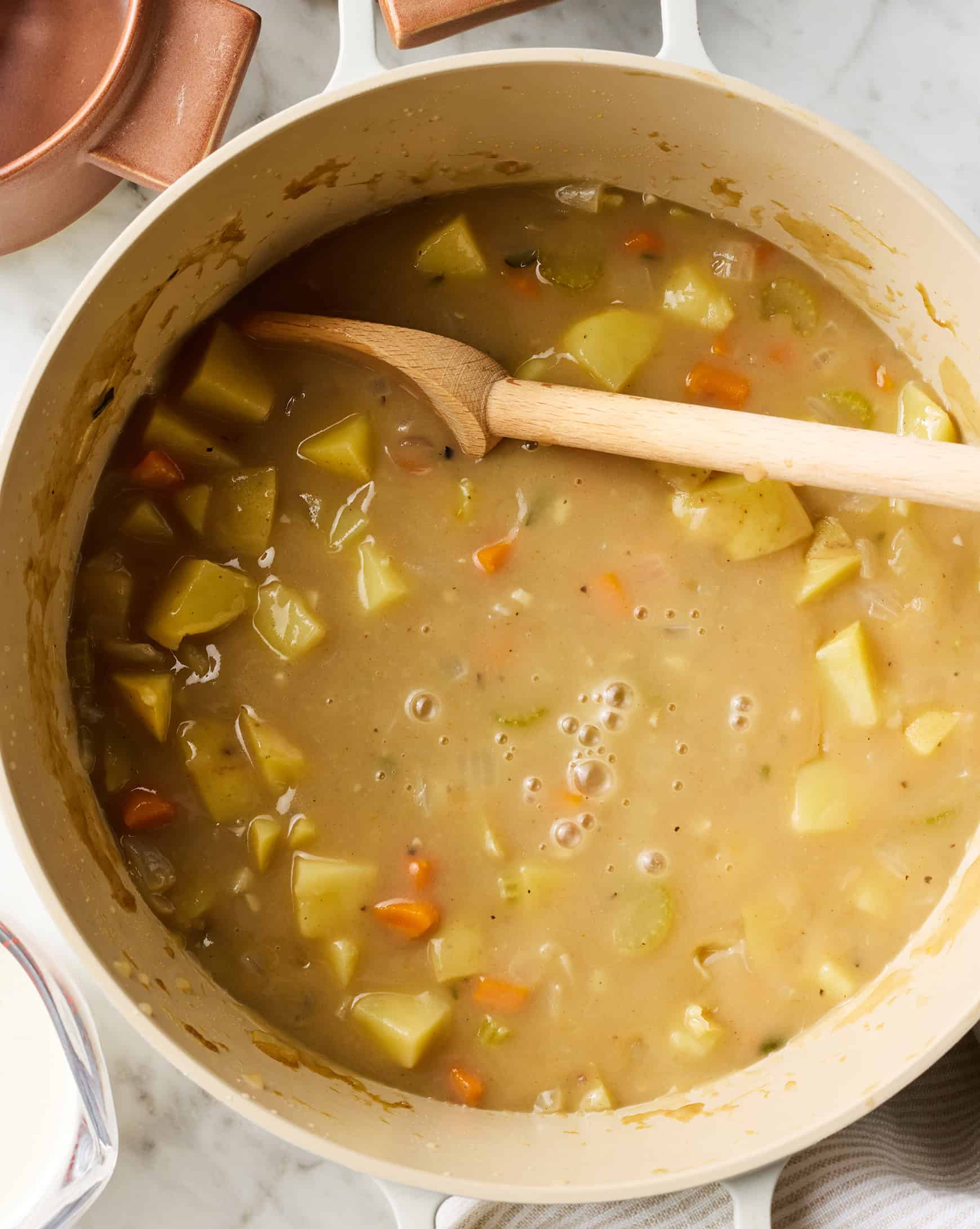 Homemade potato soup in pot with wooden spoon