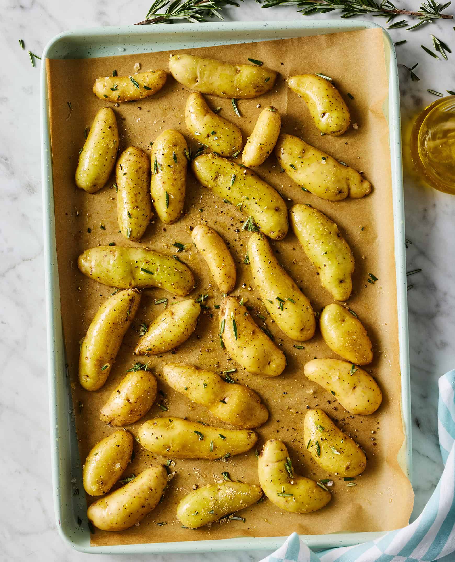 Halved potatoes cut side down on baking sheet with rosemary