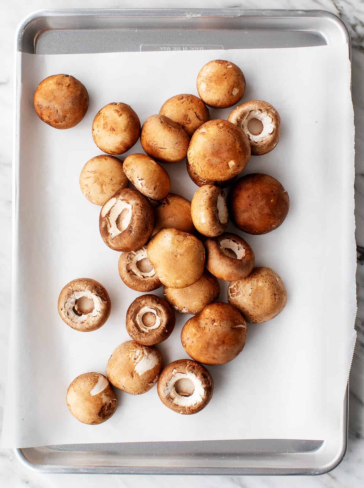 Cremini mushroom caps on a baking sheet