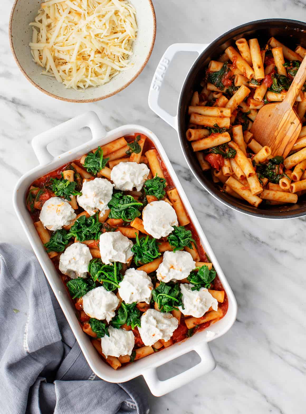 Layer of ziti and marinara topped with dollops of ricotta and spinach in a baking dish