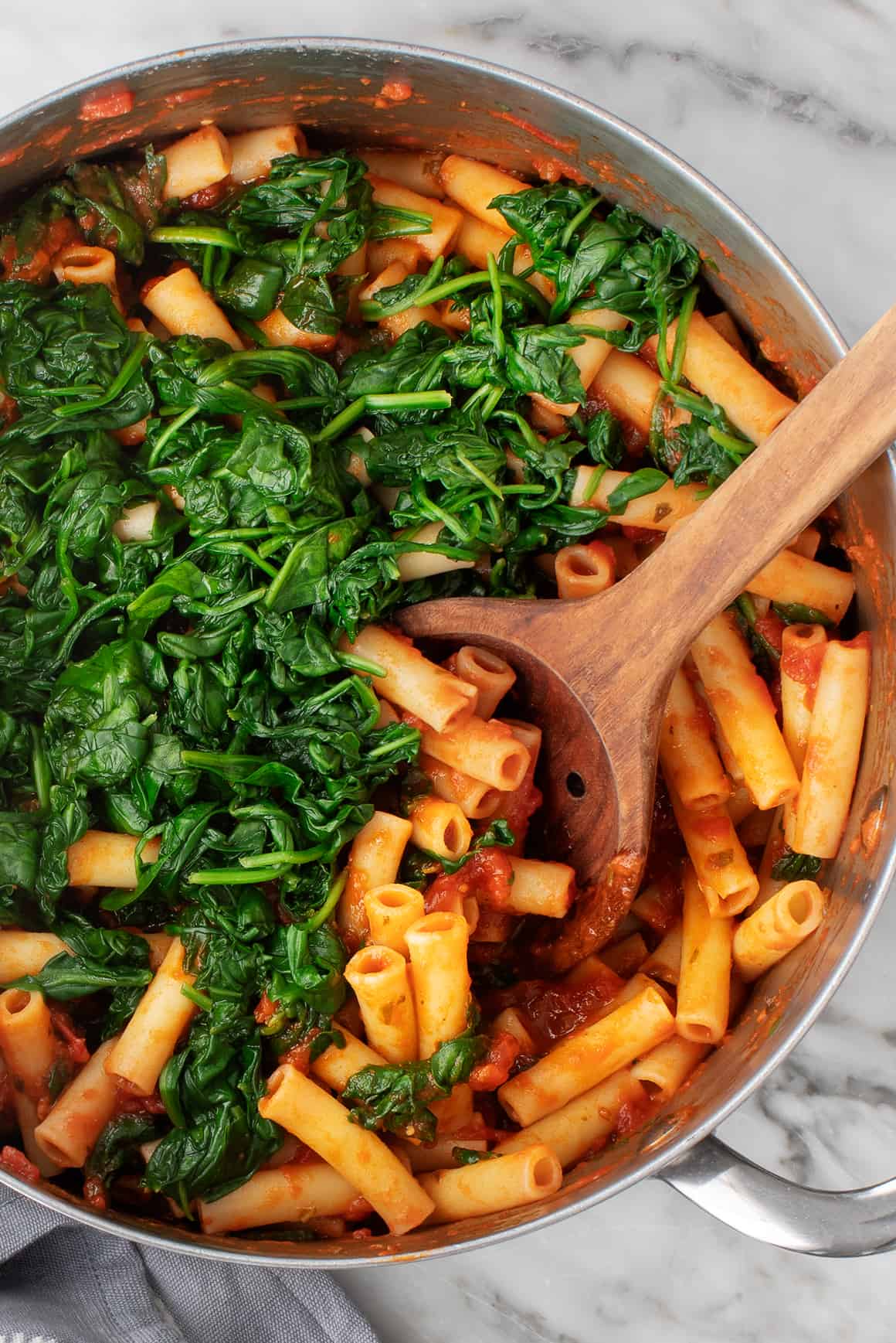 Ziti pasta in a pot with spinach and marinara sauce