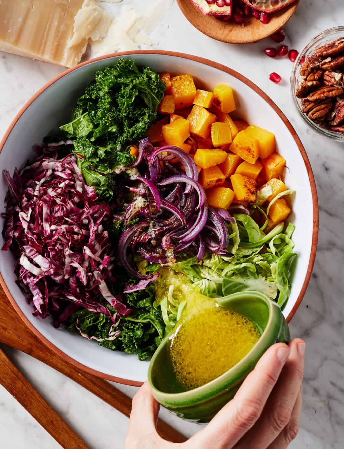 Pouring dressing over winter vegetables in a large bowl