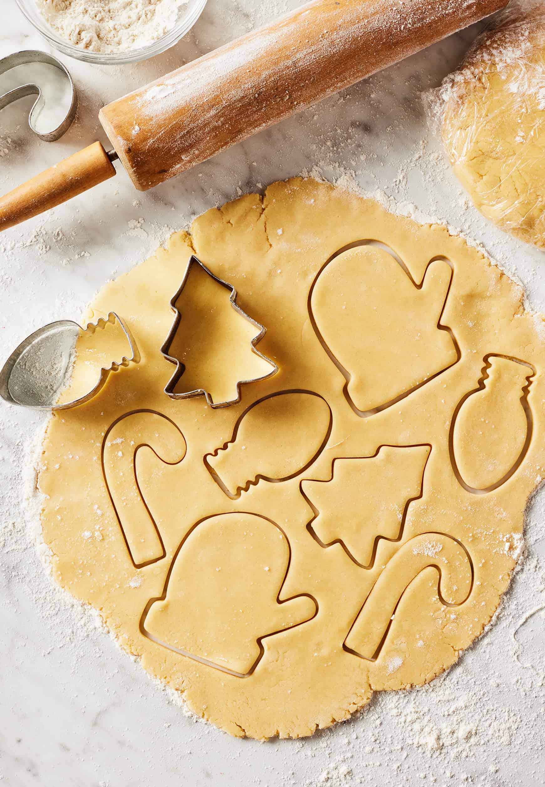 Using cookie cutters to cut out Christmas sugar cookies from dough