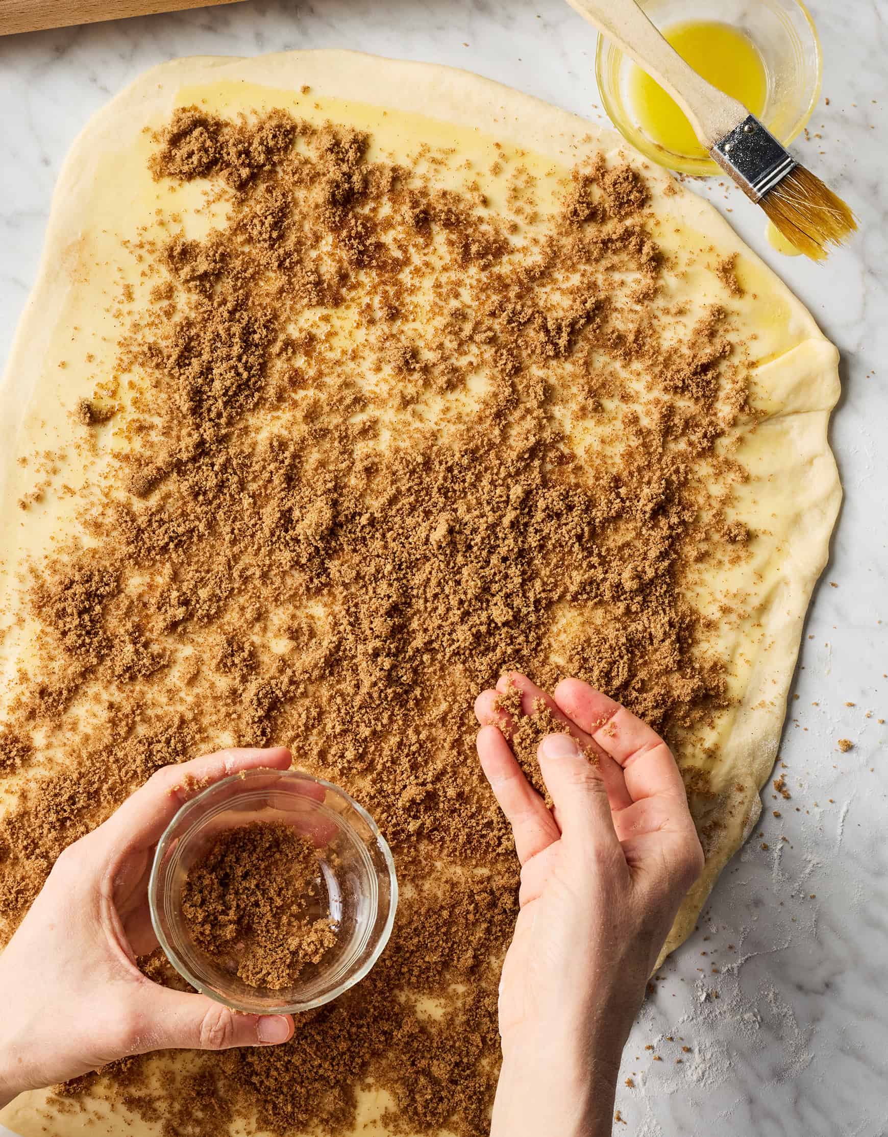 Sprinkling brown sugar and cinnamon filling over rolled out dough