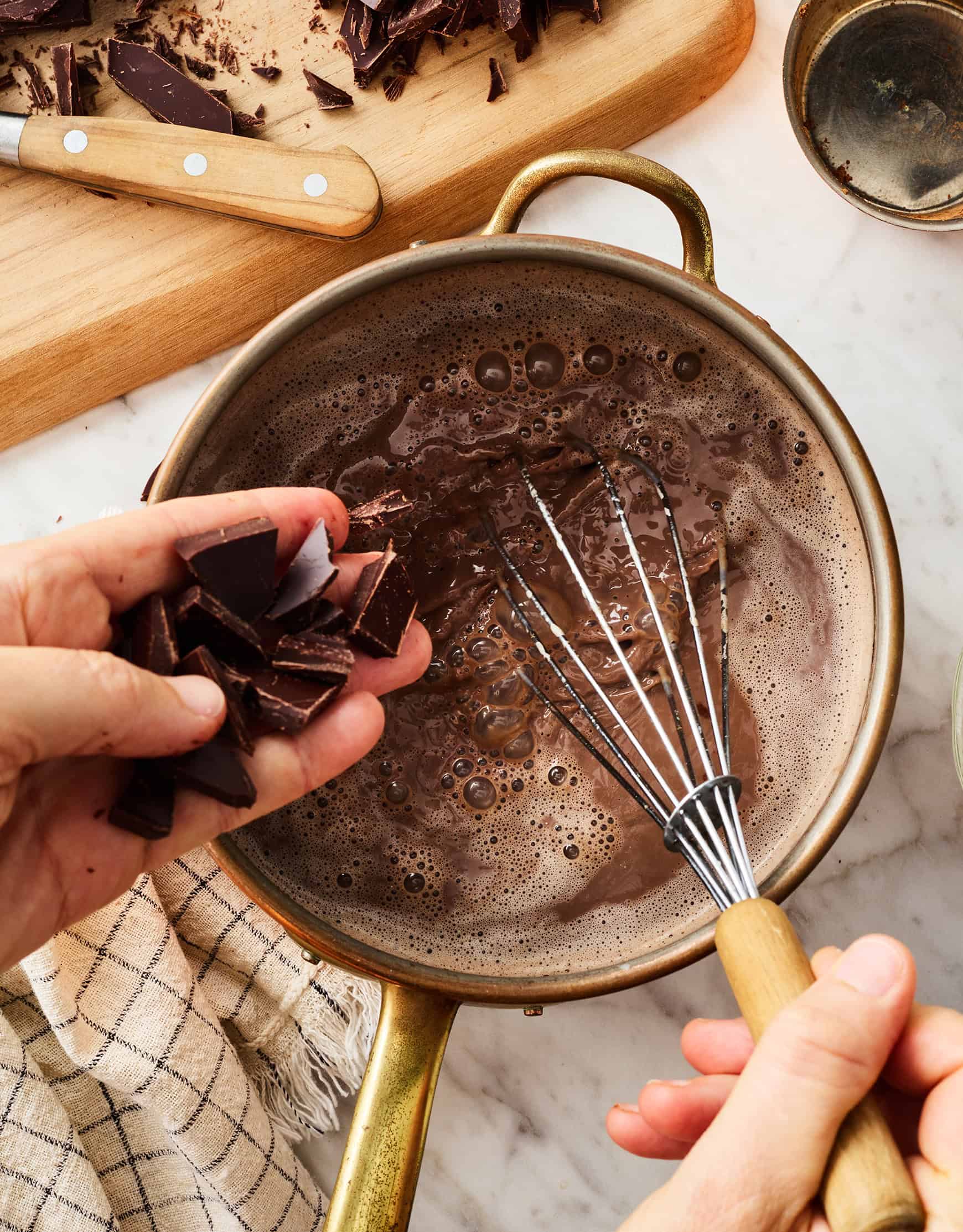 Adding chopped chocolate to saucepan while whisking