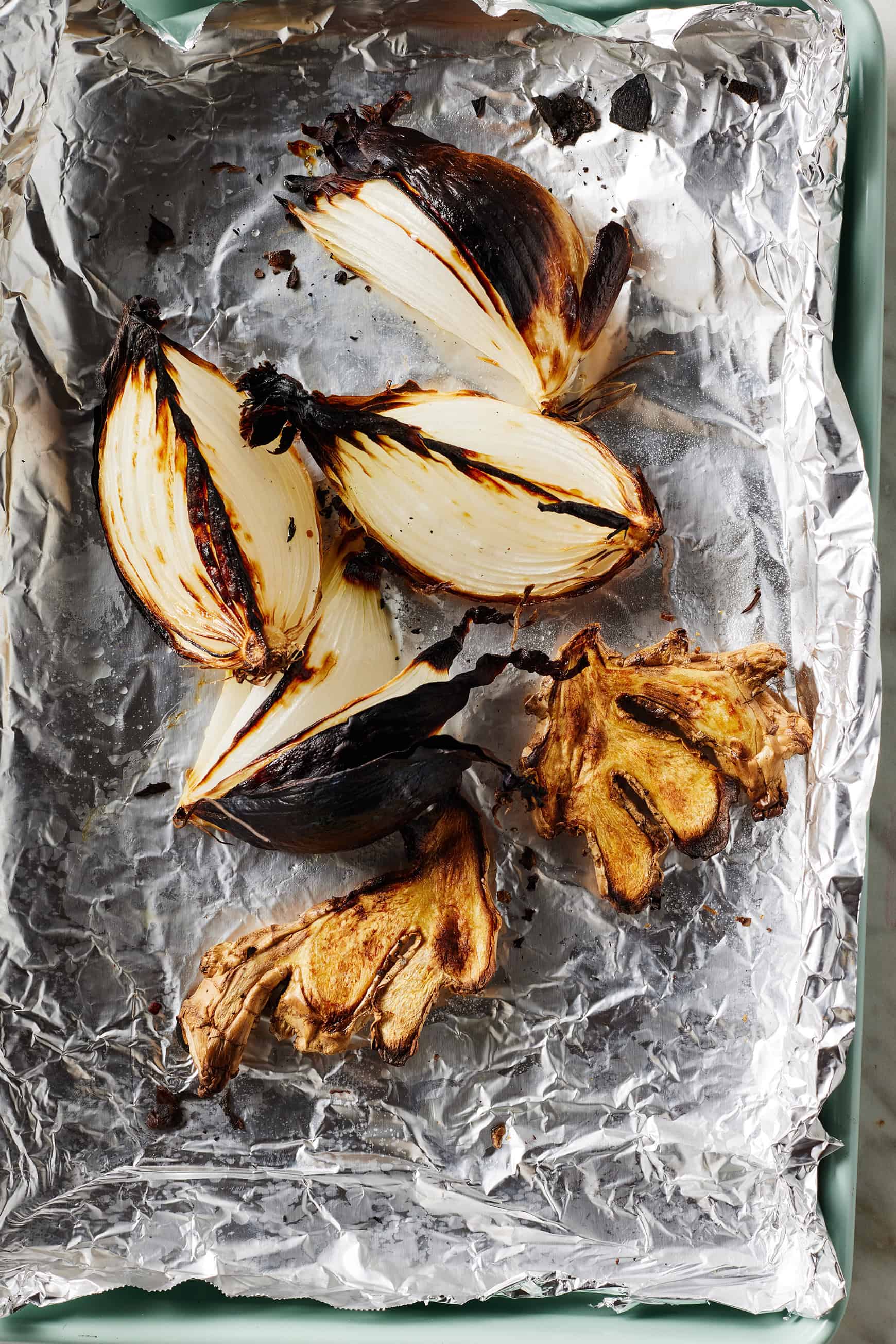 Charred onions and ginger on baking sheet lined with foil