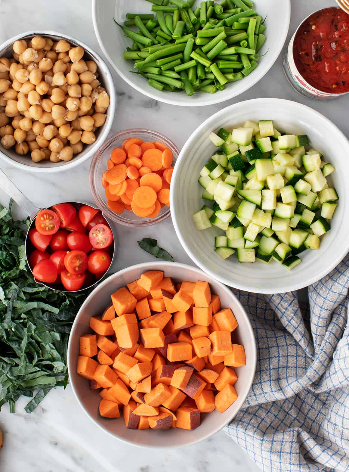 Recipe ingredients - zucchini, carrots, sweet potato, cherry tomatoes, green beans, chickpeas, kale, and canned tomatoes